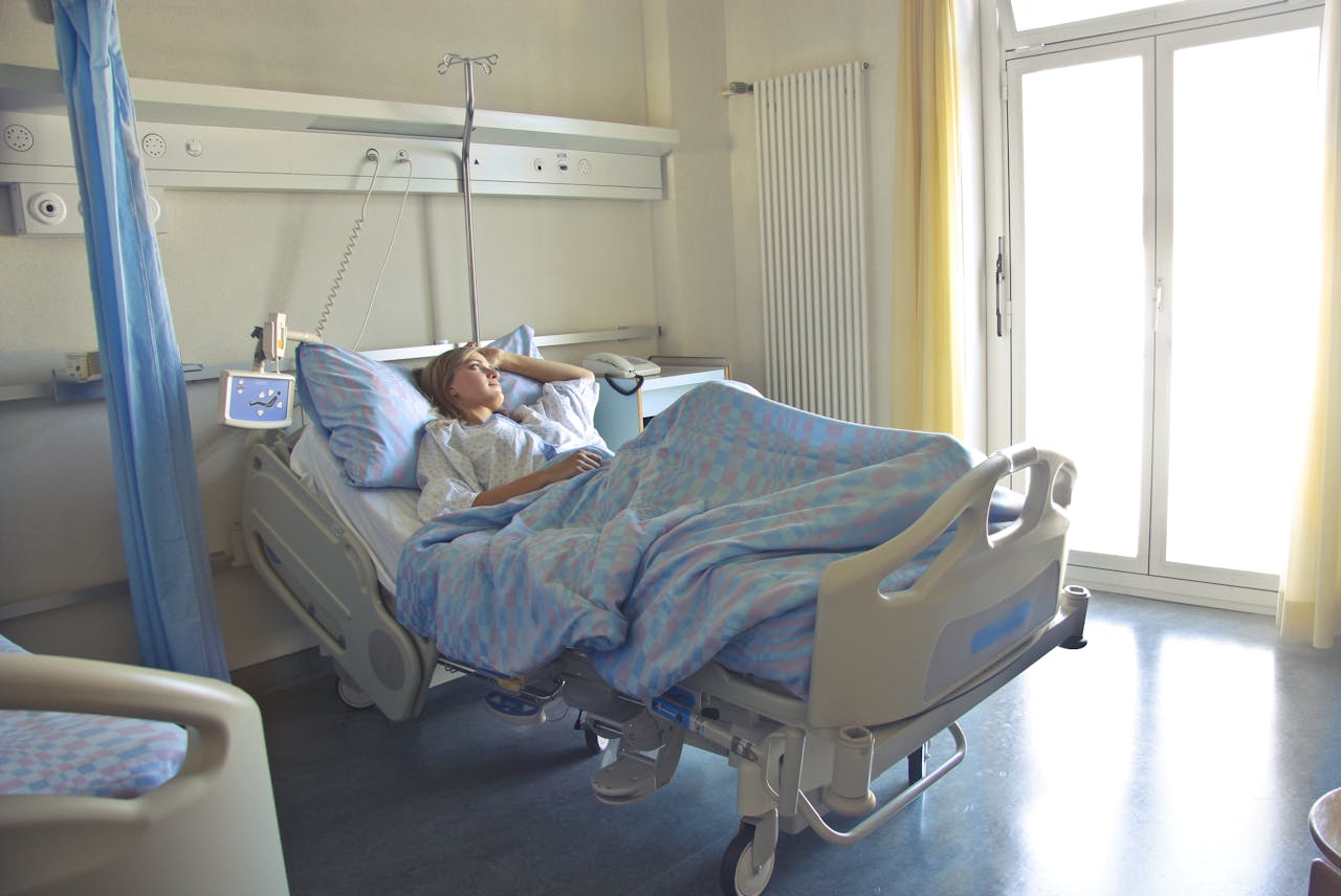 Teraphy A woman lying in a hospital bed in a bright, softly lit room, appearing to rest or recover.